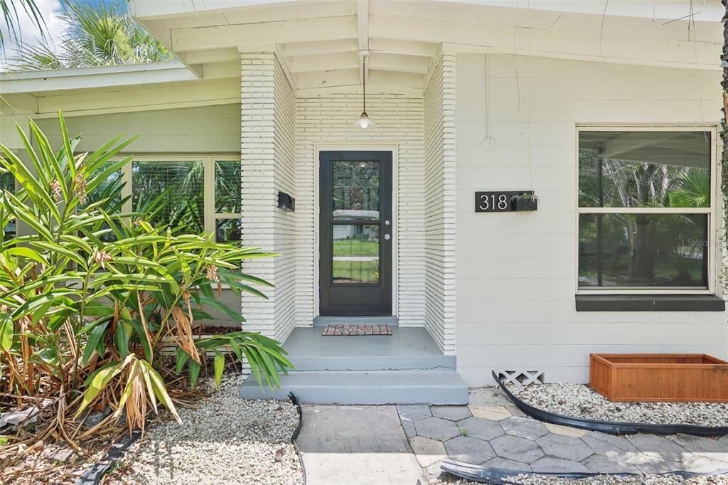 The exterior of a white house features a black front door and a brick entryway — 318 E JERSEY STREET, ORLANDO, FL