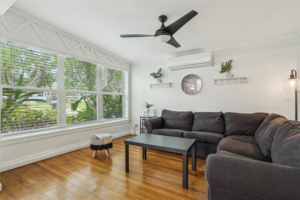 A living room with hardwood floors, a dark sectional sofa, and large windows with blinds — 318 E JERSEY STREET, ORLANDO, FL