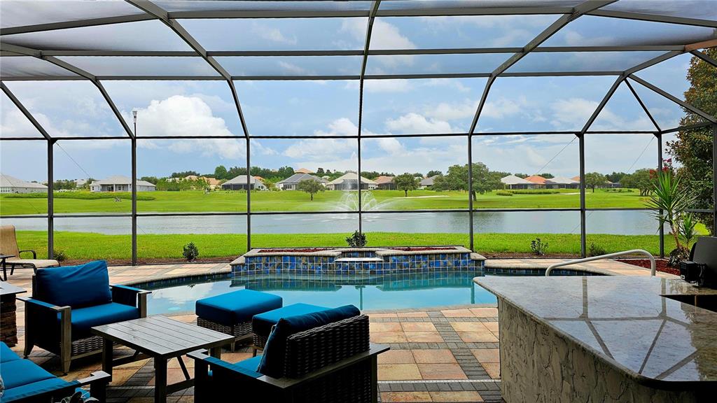 A screened-in patio features a swimming pool, a fountain, and a view of a lake — 1575 N EAGLE RIDGE PATH, HERNANDO, FL