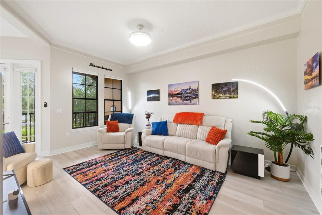 A living room features light wood flooring, a beige sofa, two armchairs, and a colorful rug — 500 MIRASOL CIRCLE UNIT 205, CELEBRATION, FL