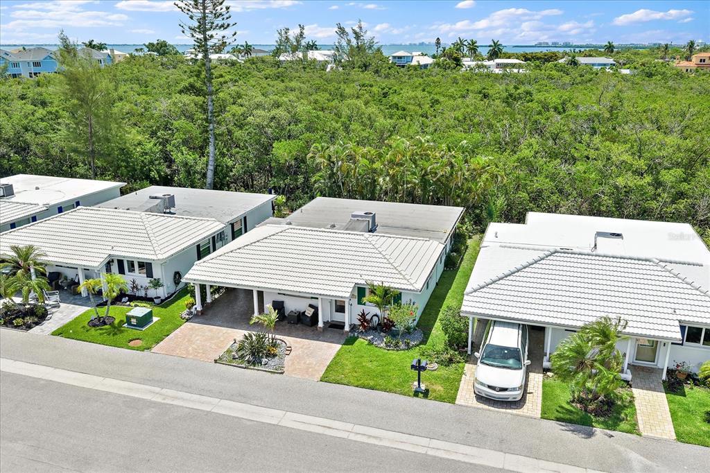 An aerial view shows three single-story houses with white roofs and carports along a street — 820 SPANISH DRIVE S UNIT ., LONGBOAT KEY, FL