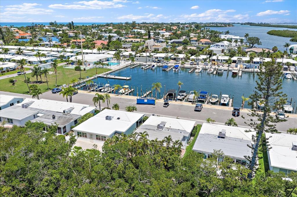 An aerial view shows a waterfront community with a marina, boat slips, and residential homes — 820 SPANISH DRIVE S UNIT ., LONGBOAT KEY, FL