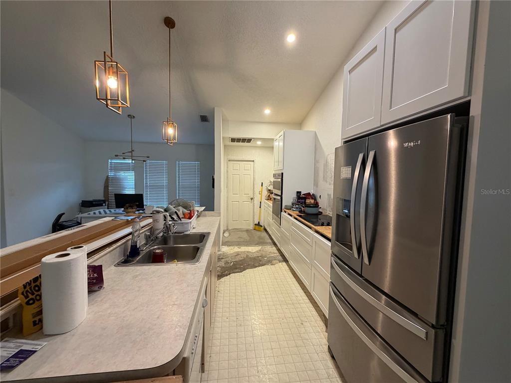 A kitchen features white cabinets, stainless steel appliances, a double sink, and unfinished flooring — 5264 BRICKELL DRIVE, NORTH PORT, FL