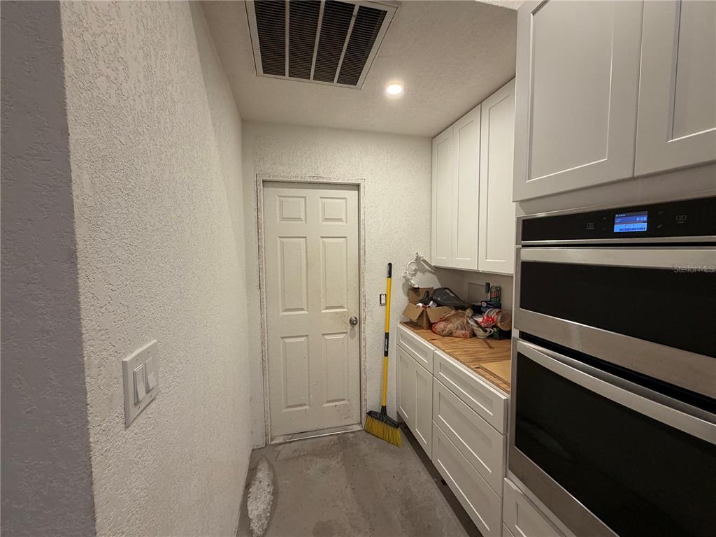A laundry room features white cabinets, a wooden countertop, a wall oven, and a door — 5264 BRICKELL DRIVE, NORTH PORT, FL