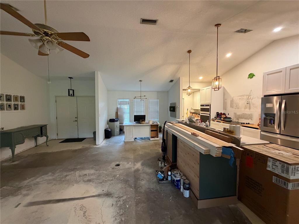 An unfinished open-concept room features a kitchen island, a desk area, and concrete flooring — 5264 BRICKELL DRIVE, NORTH PORT, FL