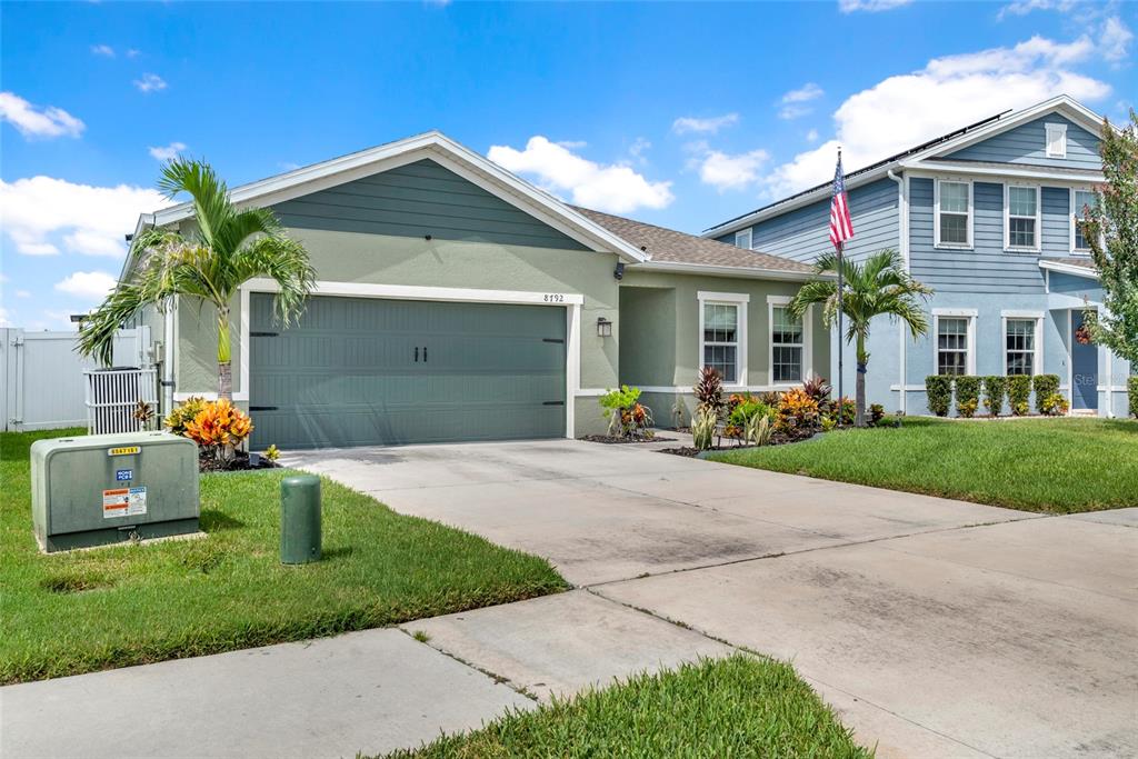 A single-story house with a green garage door and a neighboring two-story blue house — 8792 PRAIRIE CREEK DRIVE, NEW PORT RICHEY, FL