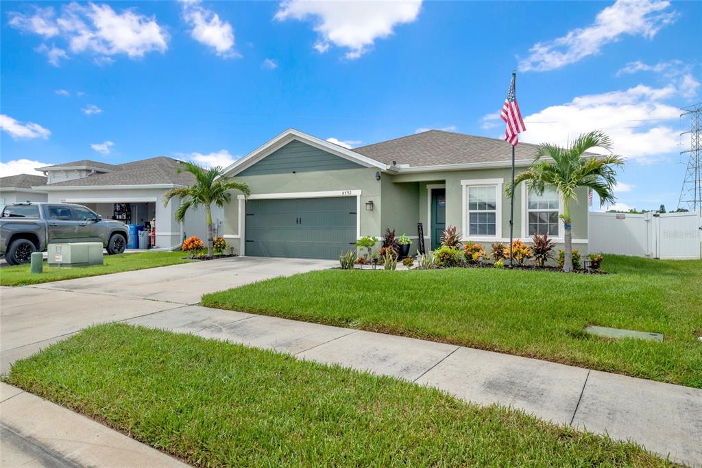 A single-story house with a green exterior, a two-car garage, and a front lawn — 8792 PRAIRIE CREEK DRIVE, NEW PORT RICHEY, FL