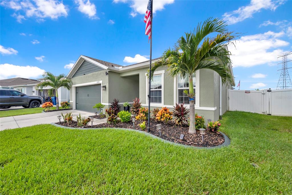 A single-story house with a green exterior, a two-car garage, and a landscaped front yard — 8792 PRAIRIE CREEK DRIVE, NEW PORT RICHEY, FL