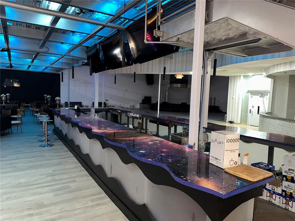 A long bar with a galaxy-patterned countertop sits in a room with blue overhead lighting — 6405 RALEIGH STREET, ORLANDO, FL