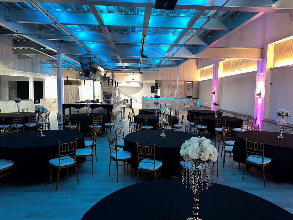 A large event space features round tables with black tablecloths and blue ceiling lighting — 6405 RALEIGH STREET, ORLANDO, FL
