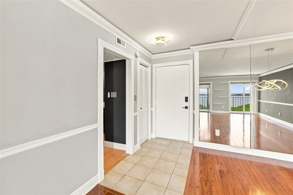 An entryway features tiled flooring, a white door, and a wall of mirrored closet doors — 19029 N US HIGHWAY 19 UNIT 9-704, CLEARWATER, FL