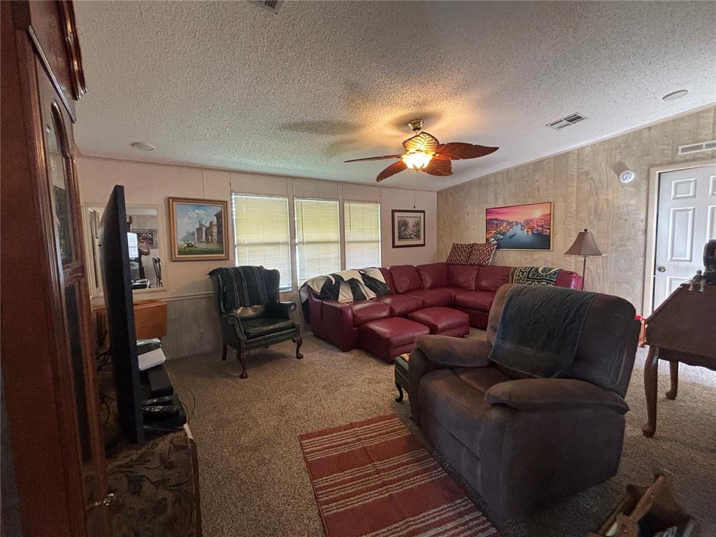 A living room features a red sectional sofa, a brown recliner, and a ceiling fan — 3725 COHEN DRIVE UNIT 717, ZELLWOOD, FL