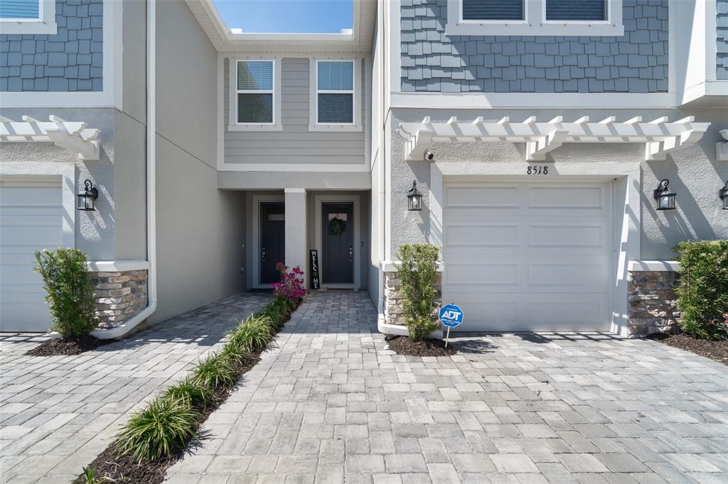 The exterior of a two-story townhouse features a paved driveway, garage, and two front doors — 8518 PRIMROSE WILLOW PLACE, ODESSA, FL