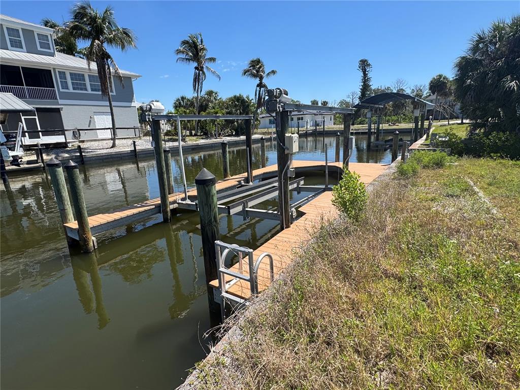 A wooden boat dock with a mechanical lift extends into a canal beside a house — 24360 BLACKBEARD BLVD, PUNTA GORDA, FL