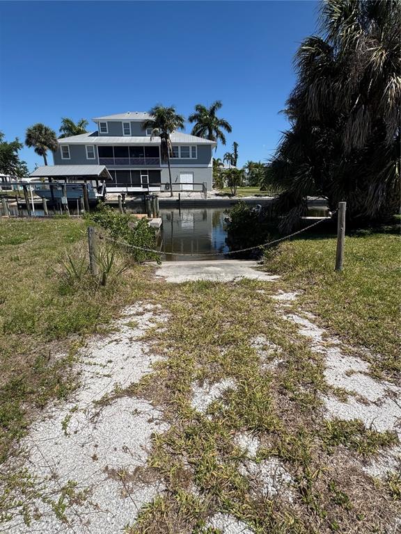 A concrete boat ramp leads into a canal in front of a two-story house — 24360 BLACKBEARD BLVD, PUNTA GORDA, FL
