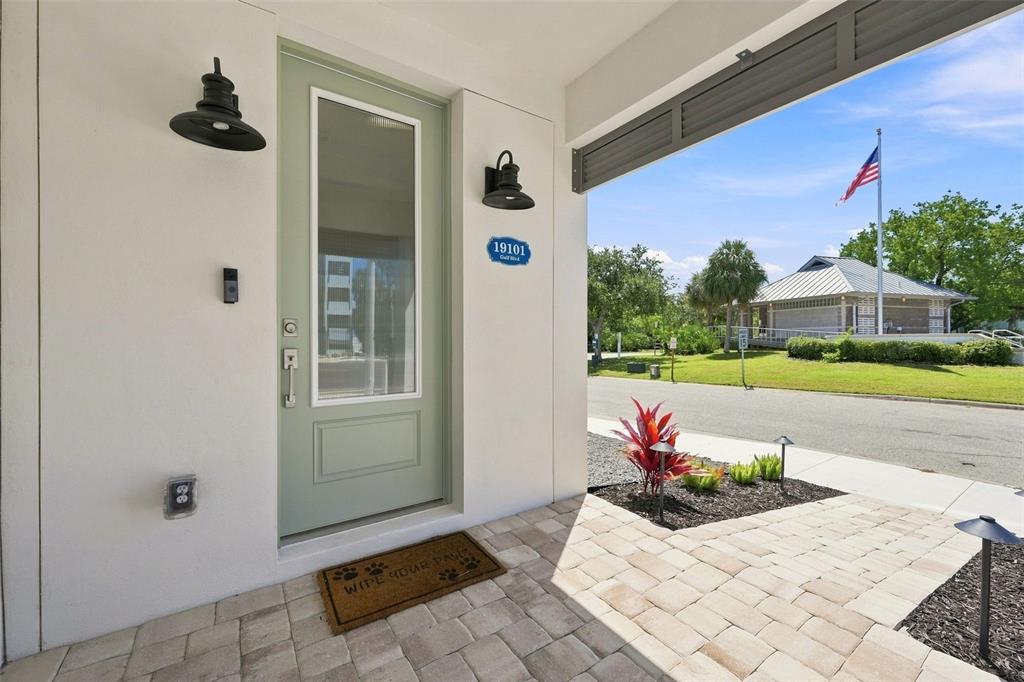 A light green front door with a glass panel sits on a paved porch — 19101 GULF BOULEVARD, INDIAN SHORES, FL