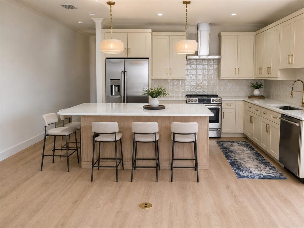 A modern kitchen features a central island with bar seating, light cabinetry, and stainless appliances — 19101 GULF BOULEVARD, INDIAN SHORES, FL