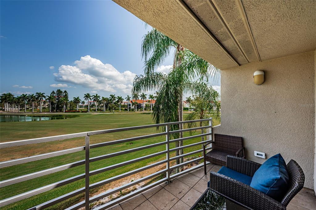 A balcony with wicker furniture overlooks a grassy golf course and a small pond — 6020 BAHIA DEL MAR CIRCLE UNIT 226, ST PETERSBURG, FL