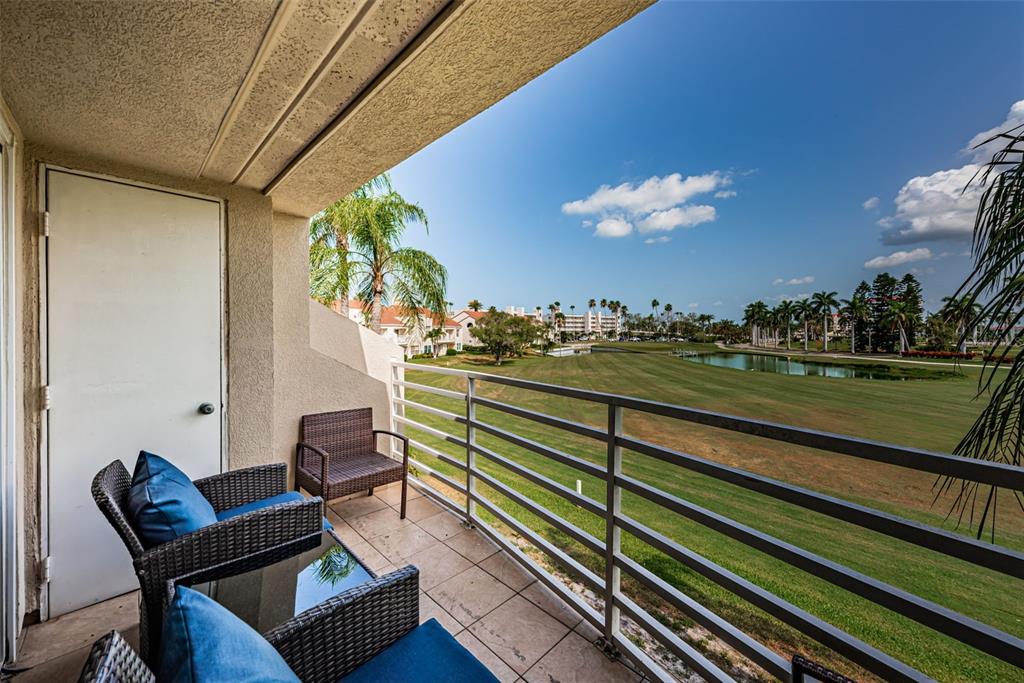 A balcony with wicker furniture overlooks a grassy golf course and a small pond — 6020 BAHIA DEL MAR CIRCLE UNIT 226, ST PETERSBURG, FL