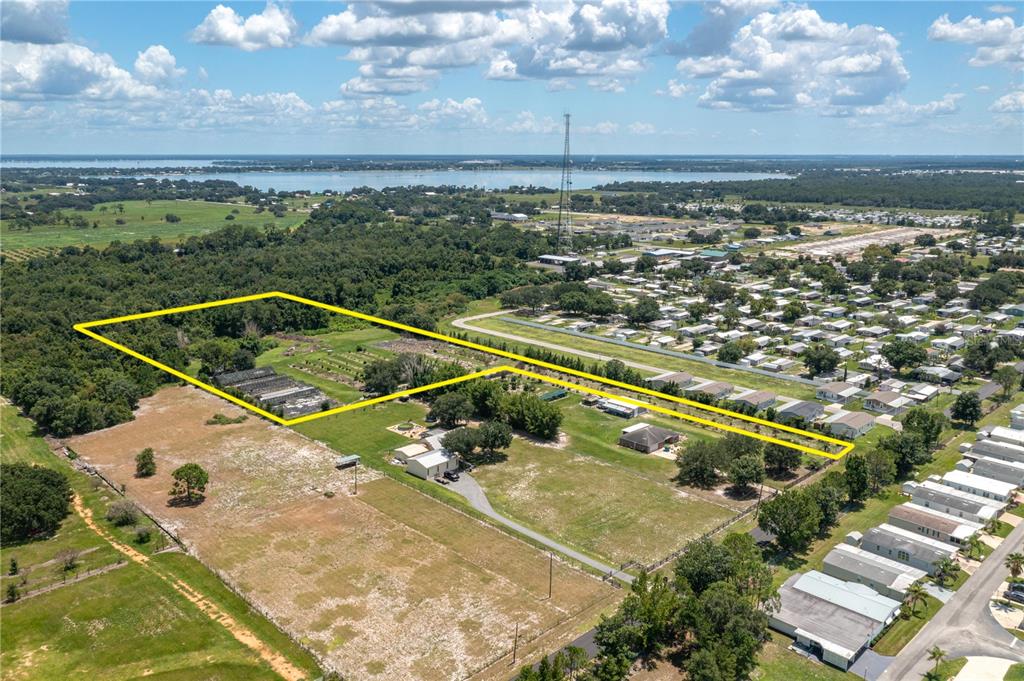 An aerial view shows a large, fenced rectangular property with greenhouses and houses nearby — 0 KEEN ROAD, FROSTPROOF, FL