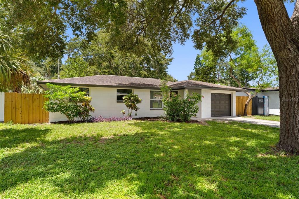 A single-story white house with a dark roof, a one-car garage, and a front lawn — 11478 92ND STREET, LARGO, FL