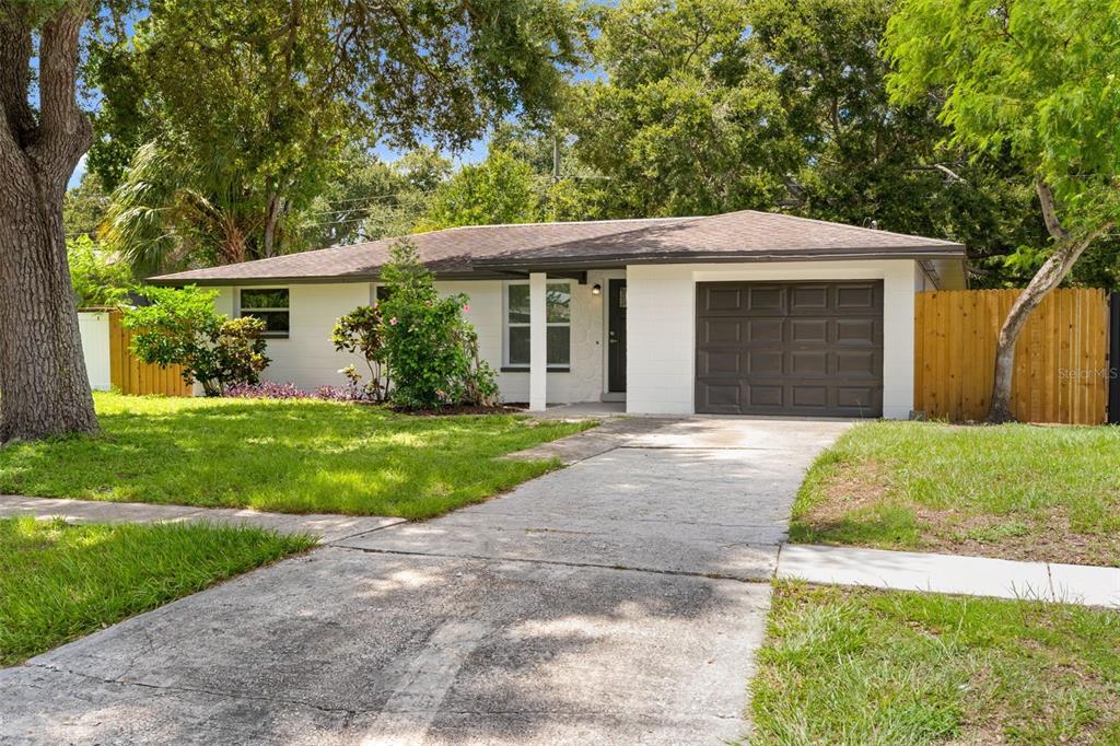 A single-story white house with a brown roof, a garage, and a concrete driveway — 11478 92ND STREET, LARGO, FL