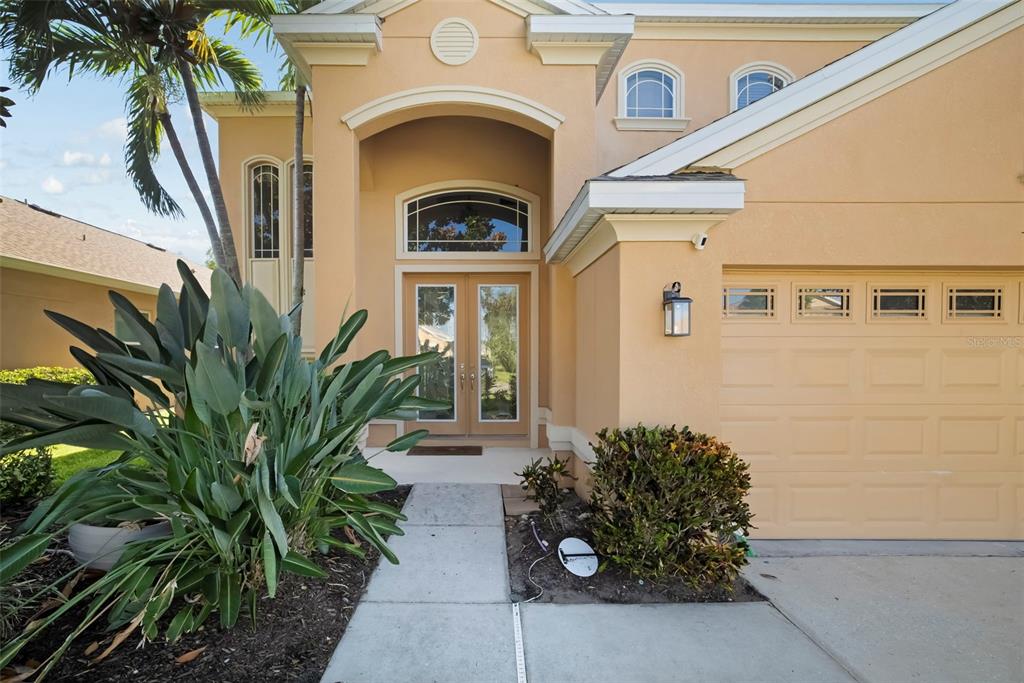A tan house exterior features a double front door, a garage, and a palm tree — 3628 SUMMERWIND CIRCLE, BRADENTON, FL
