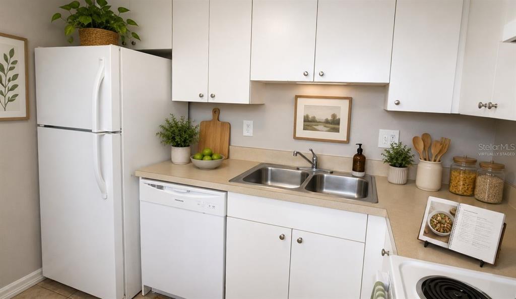 A kitchen with white cabinets, a white refrigerator, a dishwasher, and a double-basin sink — 5310 26TH STREET W UNIT 1502, BRADENTON, FL