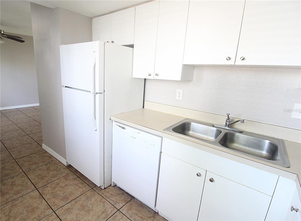 A kitchen features white cabinets, a white refrigerator, a dishwasher, and a double-basin sink — 5310 26TH STREET W UNIT 1502, BRADENTON, FL
