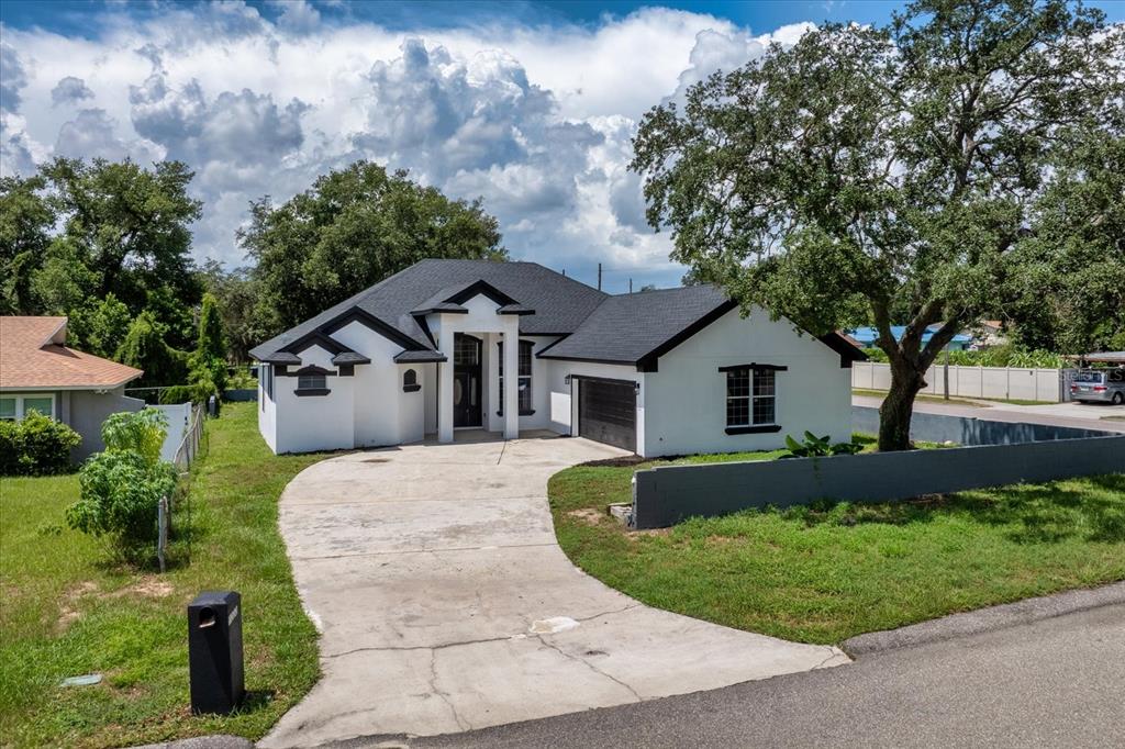 A white single-story house with a black roof, dark trim, and a concrete driveway — 1222 N HART BOULEVARD, ORLANDO, FL