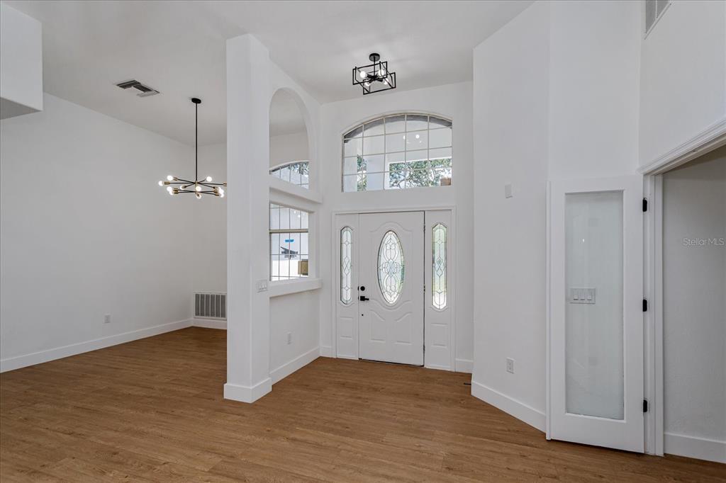 An entryway with light wood flooring, white walls, a front door, and a dining area — 1222 N HART BOULEVARD, ORLANDO, FL
