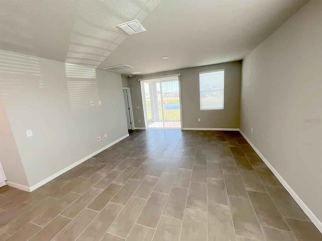 An empty room with light gray walls, tile flooring, and a sliding glass door — 820 RIVERS CROSSING STREET, CLERMONT, FL