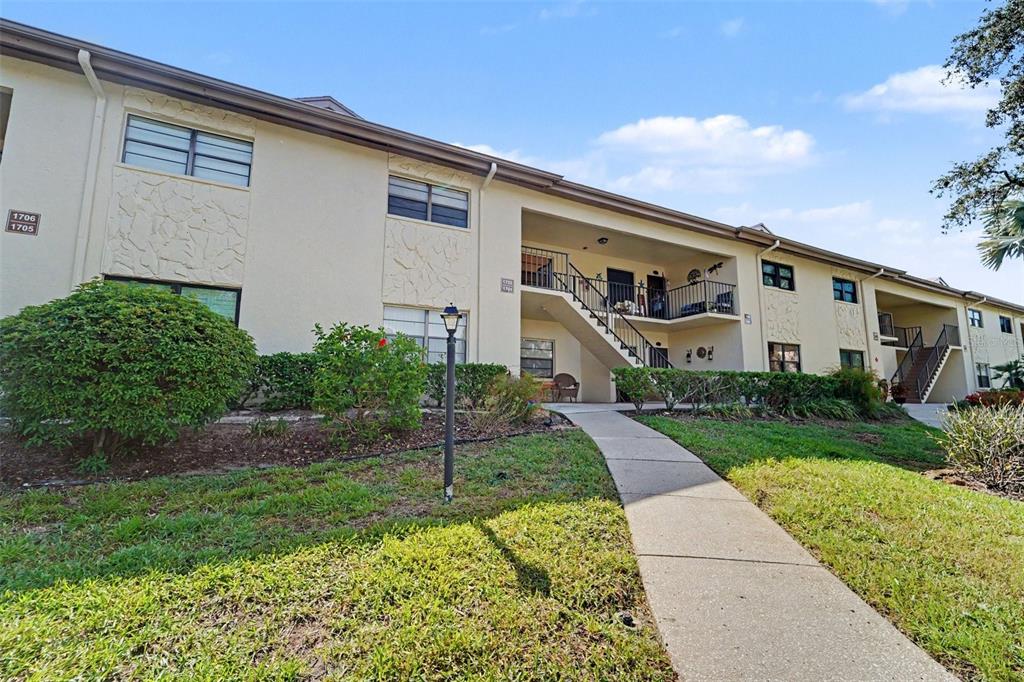 A living room features two beige sofas, a patterned rug, and a kitchen pass-through window — 1702 SEASCAPE CIRCLE UNIT 203, TARPON SPRINGS, FL