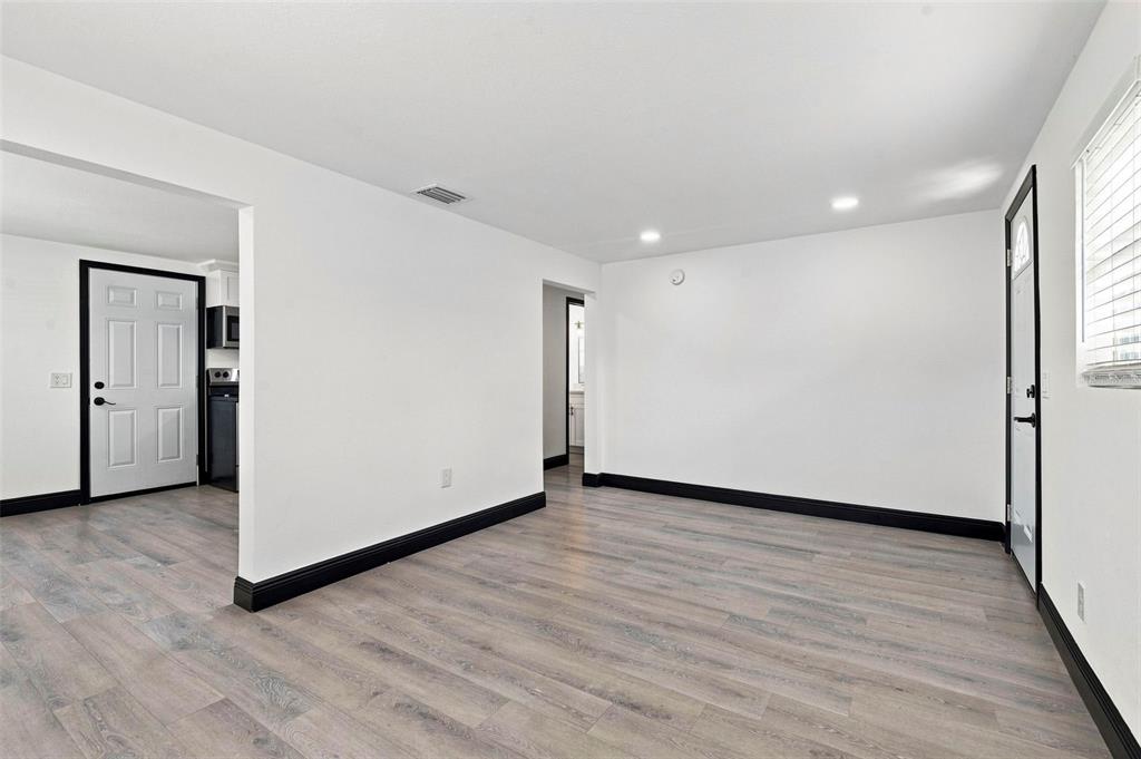 A bright room with white walls, black baseboards, and light wood-look flooring — 3611 3RD AVENUE S, ST PETERSBURG, FL