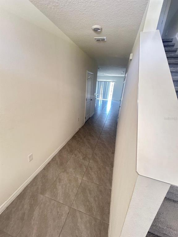 A hallway with tile flooring leads toward a doorway and a bright living area — 1471 PLANK PLACE, DAVENPORT, FL