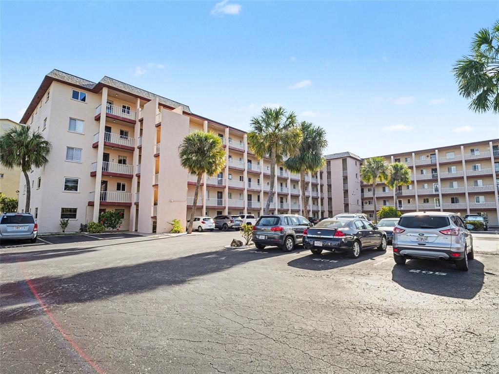 A multi-story apartment building with balconies and a paved parking lot in the foreground — 3915 LAKE BAYSHORE DRIVE UNIT 306, BRADENTON, FL
