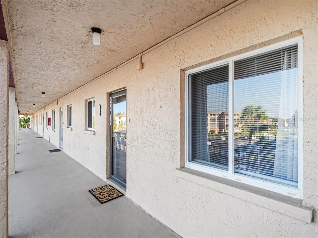 An exterior view of an apartment building walkway with a row of doors and windows — 3915 LAKE BAYSHORE DRIVE UNIT 306, BRADENTON, FL