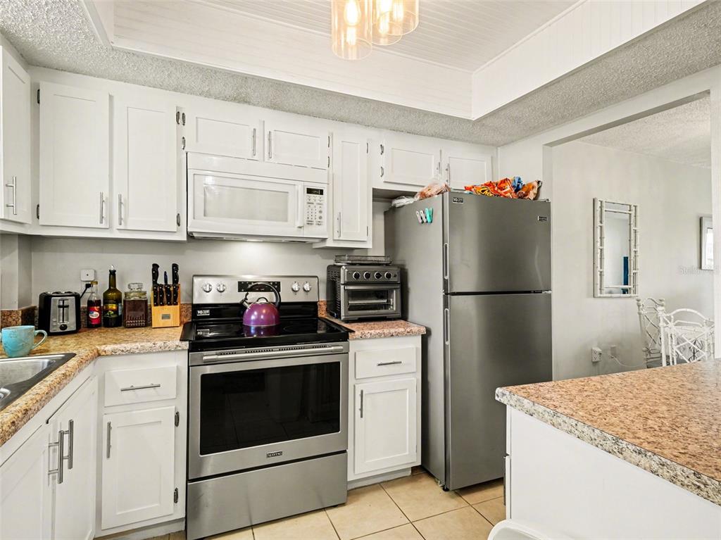 A kitchen features white cabinets, stainless steel appliances, and speckled laminate countertops — 3915 LAKE BAYSHORE DRIVE UNIT 306, BRADENTON, FL