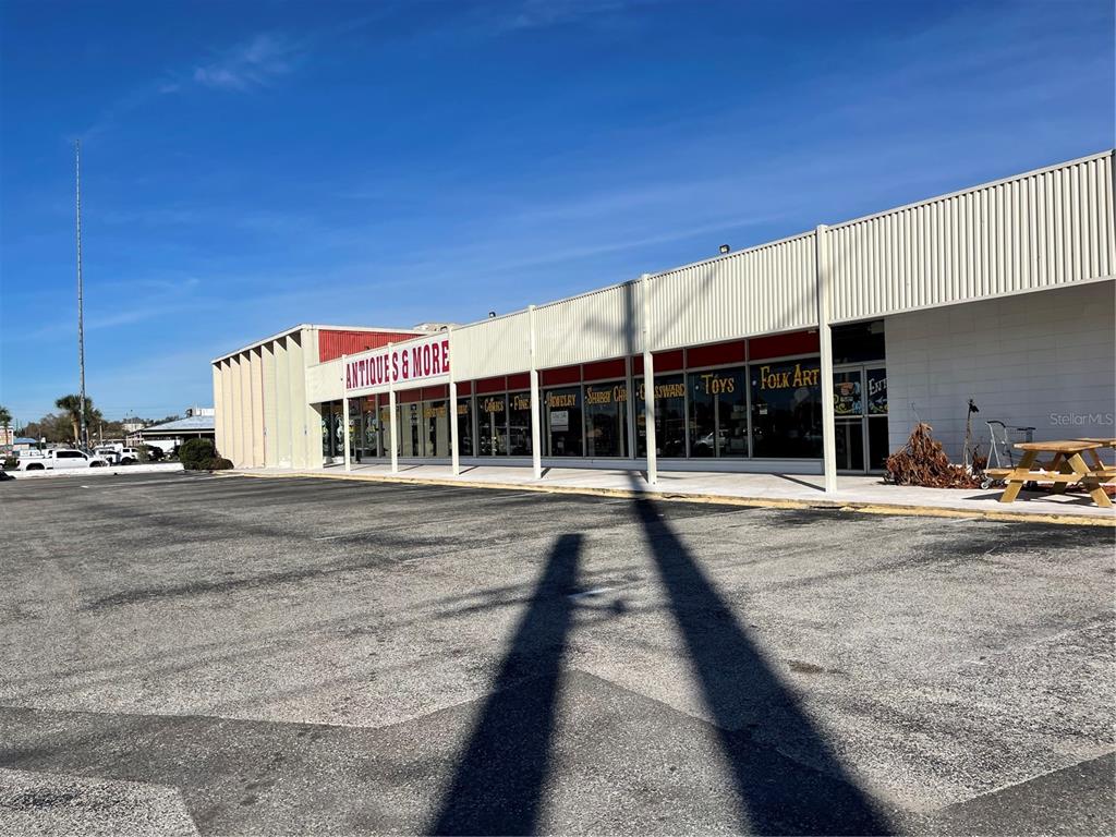 A low-rise commercial building with a large parking lot and an Antiques & More sign — 349 PLAZA DRIVE, EUSTIS, FL