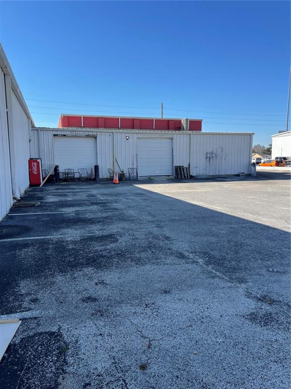 An exterior view of a commercial building with two roll-up doors and a parking lot — 349 PLAZA DRIVE, EUSTIS, FL