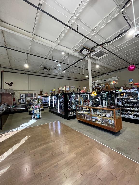 A retail store interior features wood-look flooring, high ceilings with exposed ductwork, and glass display cases — 349 PLAZA DRIVE, EUSTIS, FL