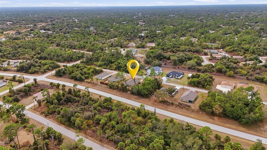 An aerial view shows a house marked with a yellow pin in a wooded neighborhood — 5708 BANNOCK CIRCLE, NORTH PORT, FL