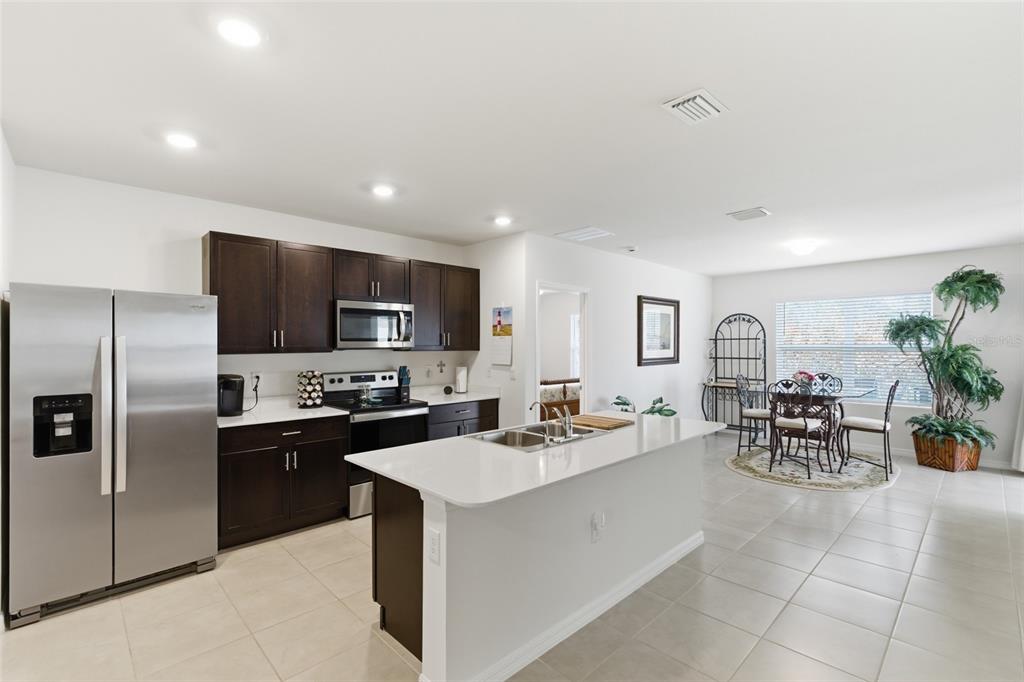 A kitchen with dark wood cabinets, stainless steel appliances, and a white quartz island — 5708 BANNOCK CIRCLE, NORTH PORT, FL