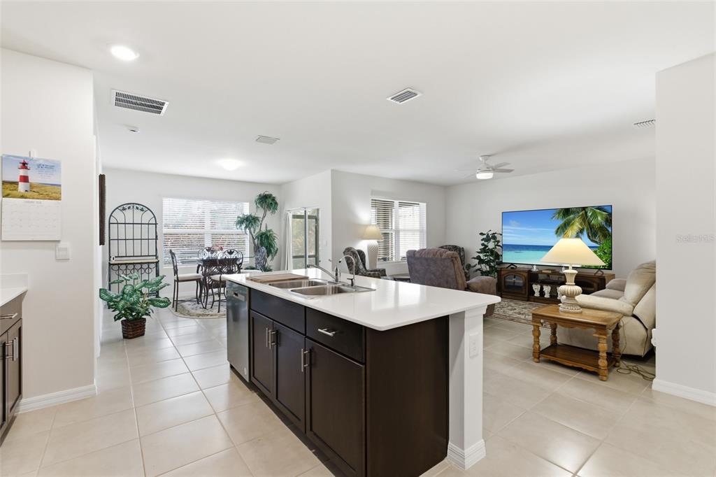 A kitchen island with a white countertop sits in an open-concept living and dining area — 5708 BANNOCK CIRCLE, NORTH PORT, FL