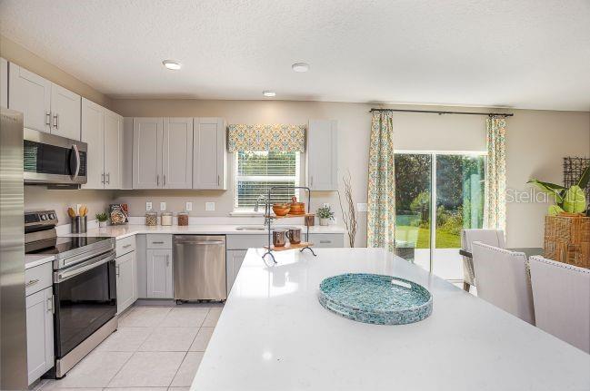 A kitchen with light gray cabinets, stainless steel appliances, and a large white quartz island — 621 BROADOAK DRIVE, DUNDEE, FL