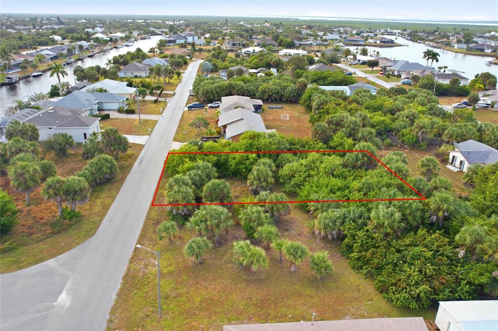 An aerial view shows a vacant, wooded residential lot outlined in red along a street — 4073 ROSE ARBOR CIRCLE, PORT CHARLOTTE, FL