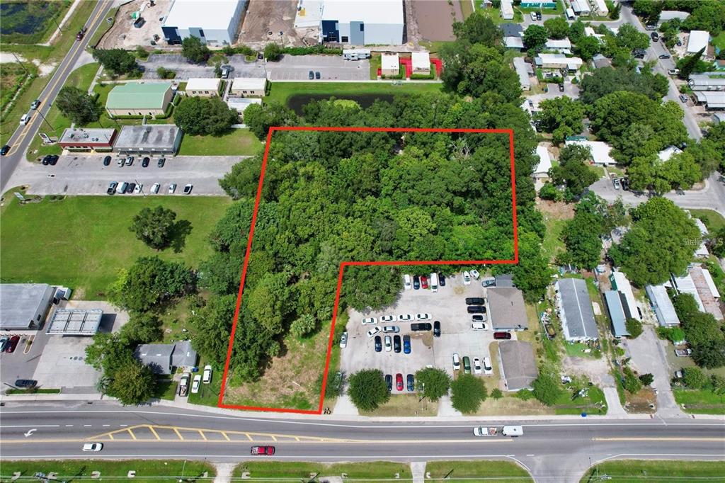 An aerial view shows a wooded, L-shaped vacant lot outlined in red next to parking lots — 319 W SILVER STAR ROAD, OCOEE, FL
