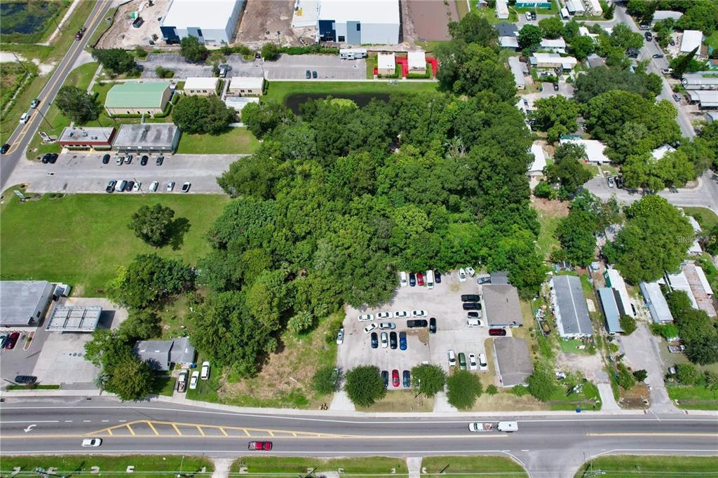An aerial view shows a wooded lot situated between commercial buildings and a paved road — 319 W SILVER STAR ROAD, OCOEE, FL