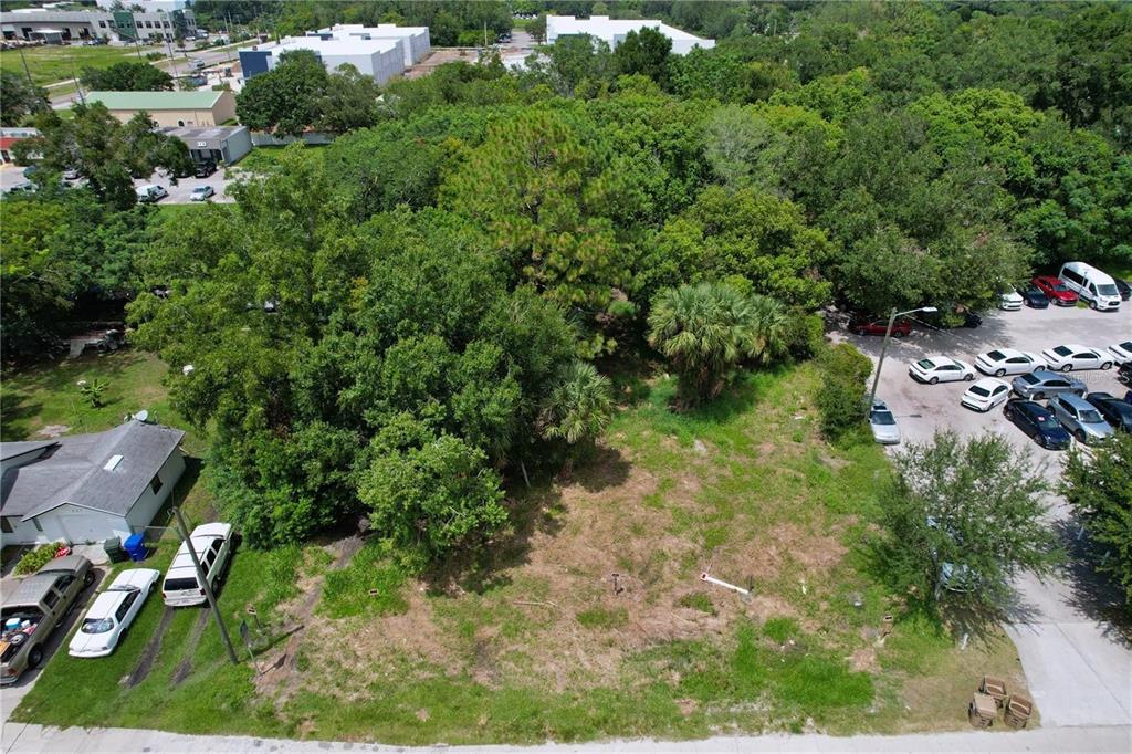 An aerial view shows a vacant, grassy lot bordered by trees, a parking lot, and houses — 319 W SILVER STAR ROAD, OCOEE, FL