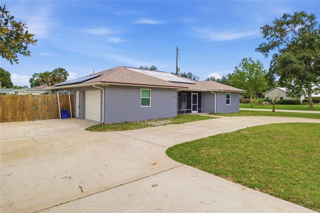 A gray, single-story house with a concrete driveway, a garage, and solar panels on the roof — 602 LAKE DRIVE, SEBASTIAN, FL